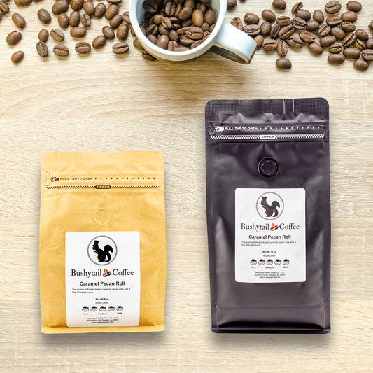 Two coffee packages from Bushytail Coffee on a wooden surface with scattered coffee beans.
