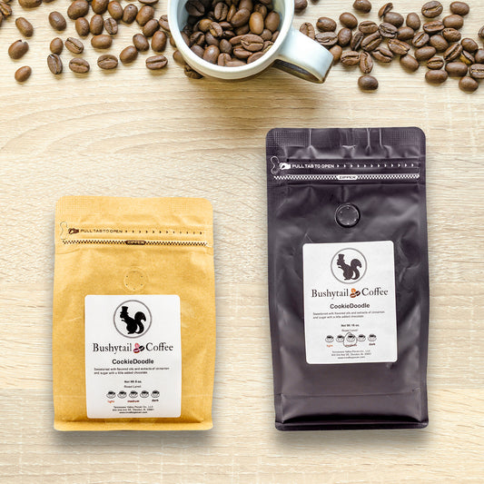 Two coffee packages from Bushytail Coffee on a wooden surface with scattered coffee beans.