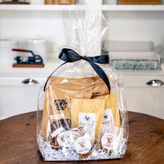 Gift basket in clear cellophane wrap with a black ribbon, set against a kitchen background.