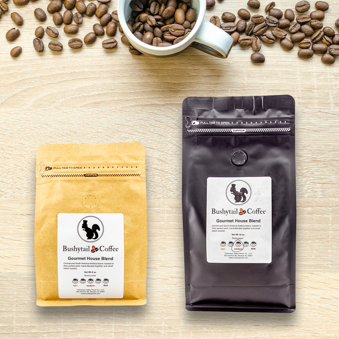 Two coffee packages from Bushytail Coffee on a wooden surface with scattered coffee beans.