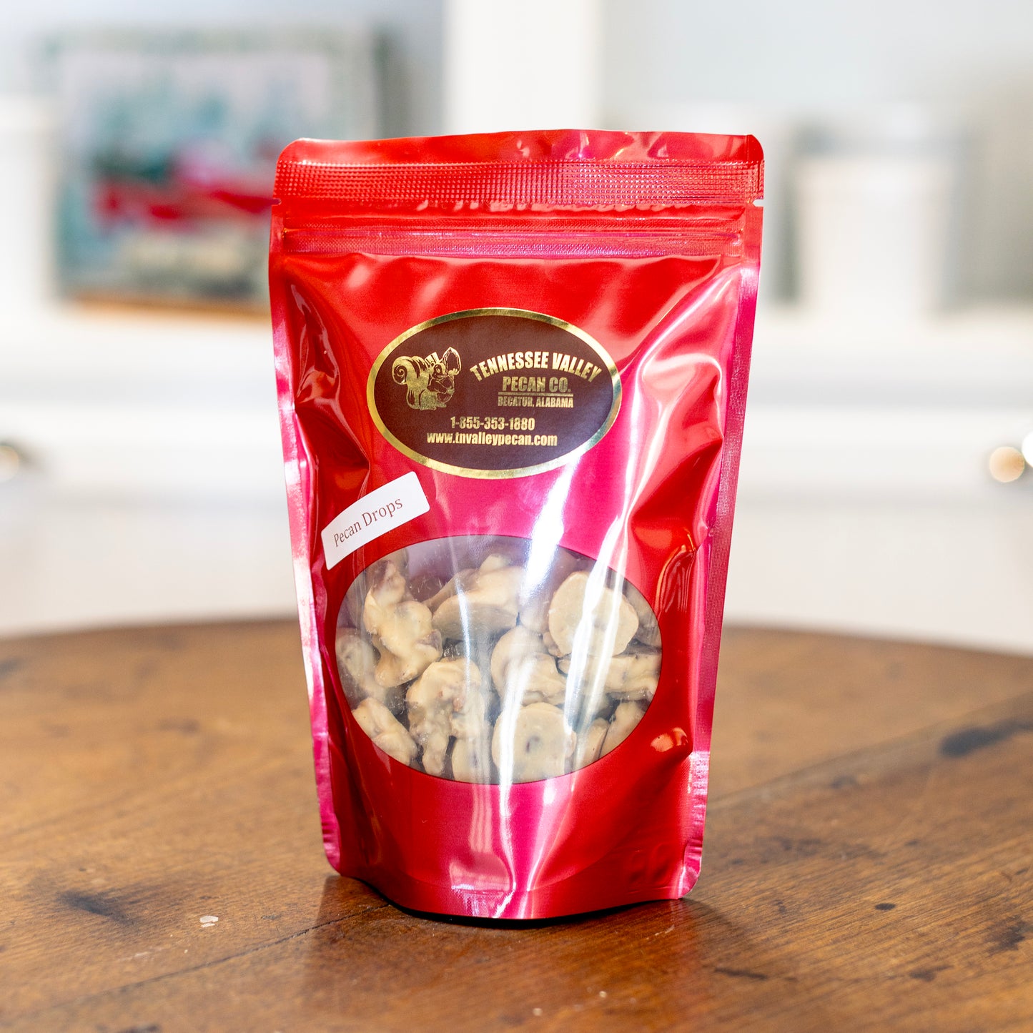 Red package of Tennessee Valley Pecan Drops on a wooden surface with a blurred background