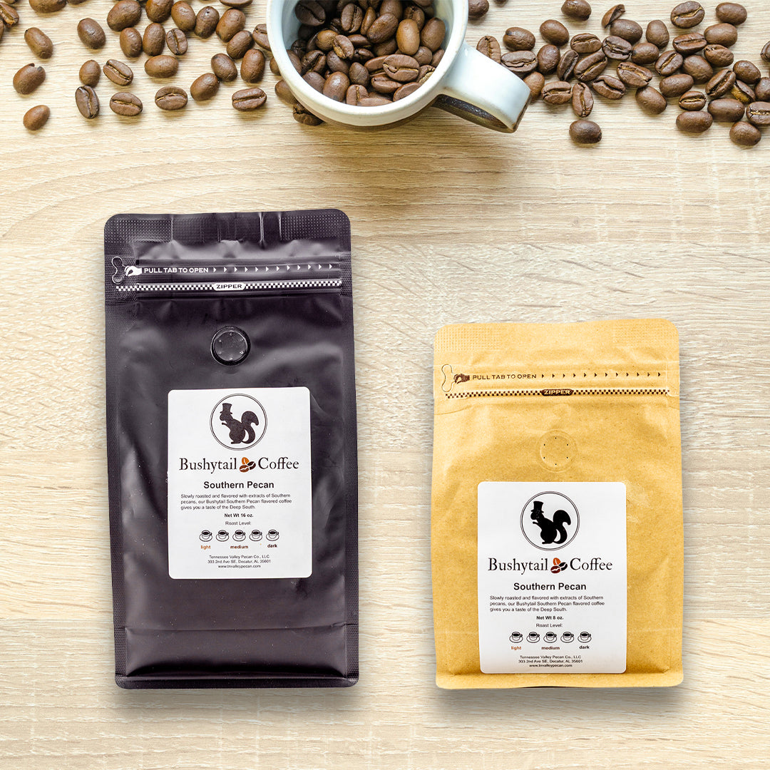 Two coffee bags from Bushytail Coffee on a wooden surface with coffee beans and a cup.