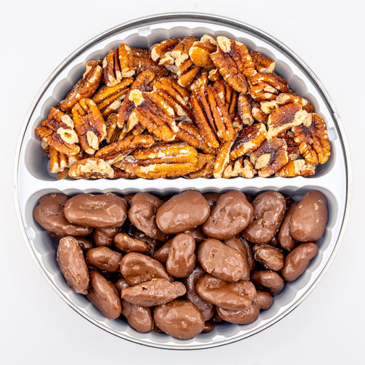 Toasted and milk chocolate pecans in a divided tin on white background.