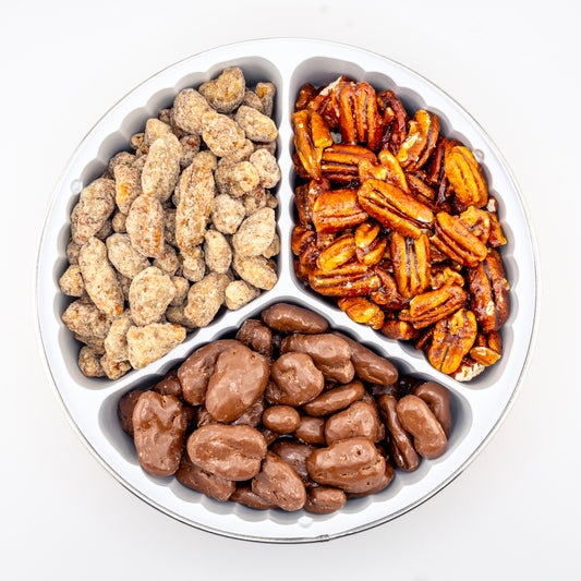 Praline, Honey glazed, and milk chocolate pecans in a divided tin on a white background