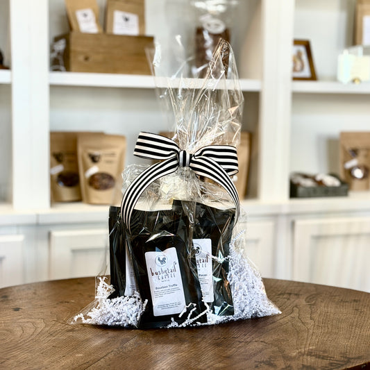 Gift bag with black and white striped bow containing coffee sample bags on a wooden table.