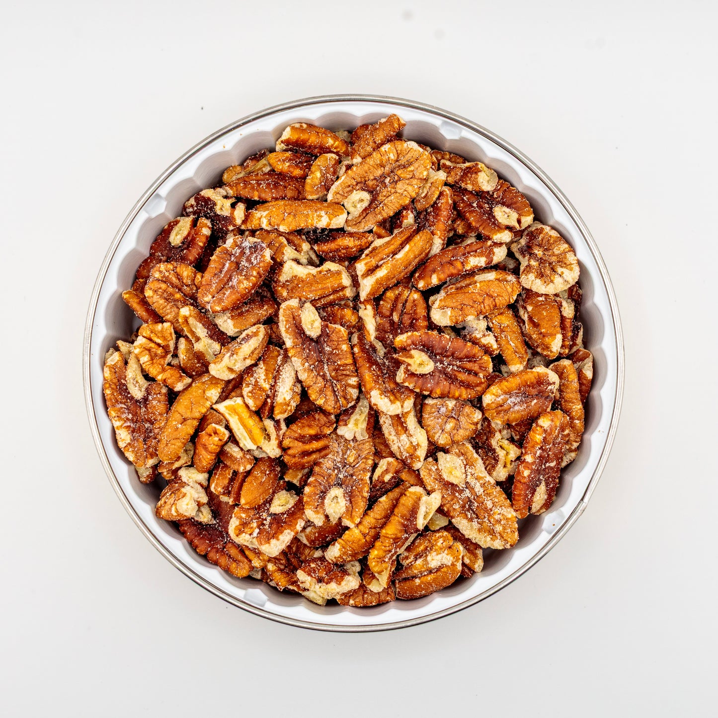 Pecans in a metal tin on a white background