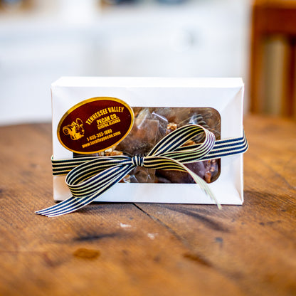 Gift box with a striped ribbon on a wooden surface, featuring a Tennessee Valley Vegan Co. label.