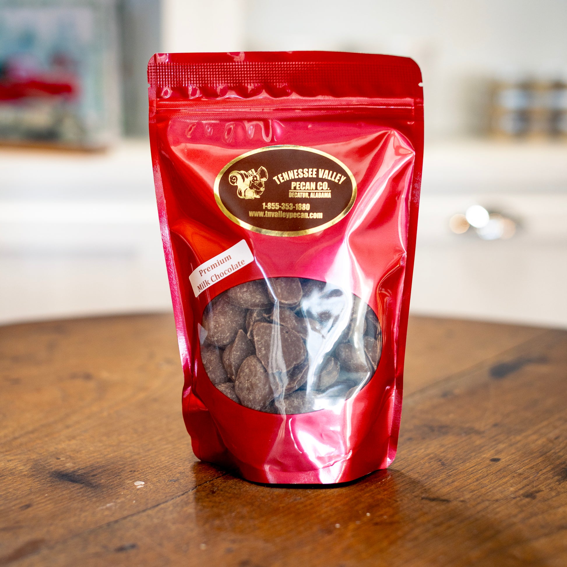Red package of Tennessee Valley Pecan Co. premium milk chocolate pecans on a wooden surface