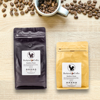 Two coffee bags from Bushytail Coffee on a wooden surface with coffee beans and a cup.