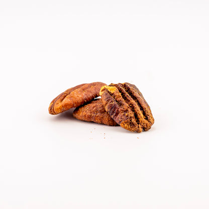 Three spicy flavored pecans on a clean white background, showing their rich brown color and textured shells.