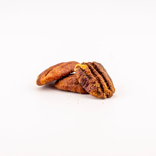 Three spicy flavored pecans on a clean white background, showing their rich brown color and textured shells.