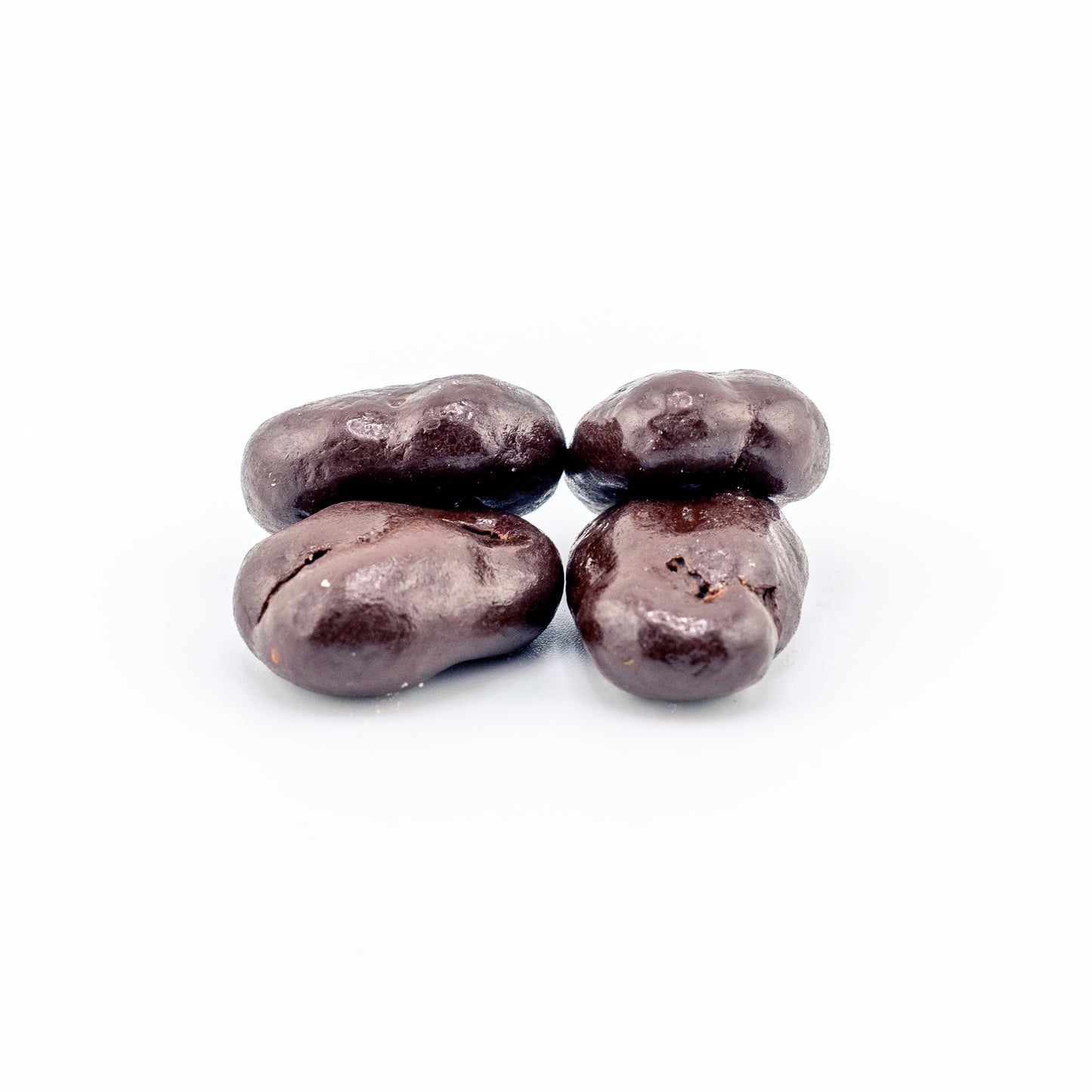 Four dark chocolate-covered pecans on a white background