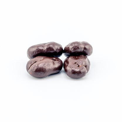 Four dark chocolate-covered pecans on a white background