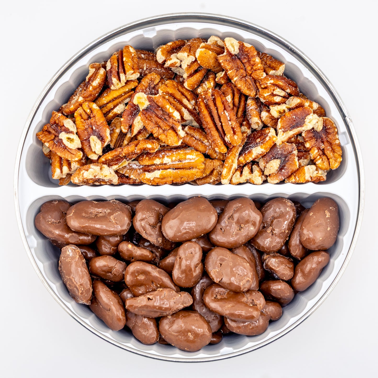 Toasted and milk chocolate pecans in a divided tin on white background.