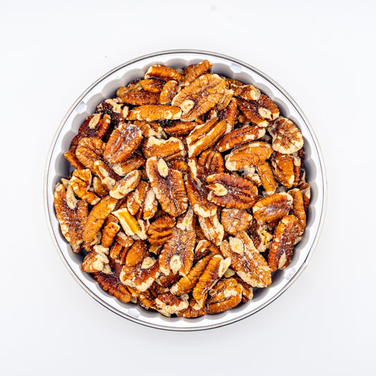 Toasted pecans in a tin on white background.