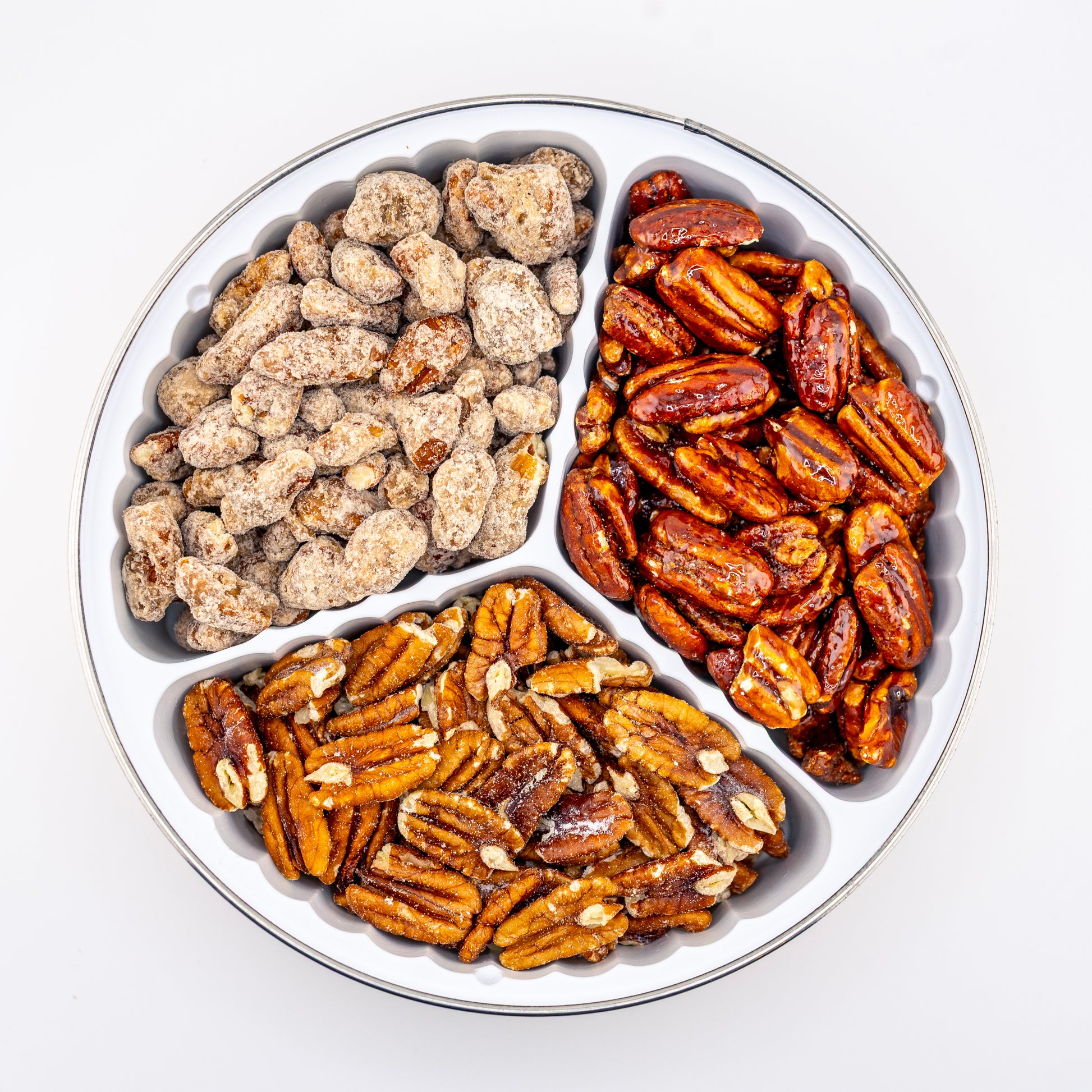 Praline, Honey glazed, and toasted pecans in a divided tin on a white background
