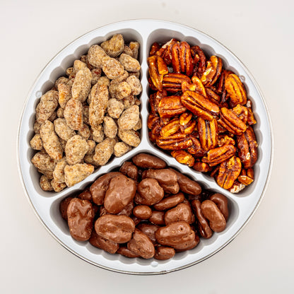 Praline, Honey-Glazed, and Milk Chocolate Pecans in a gift tin on a white background