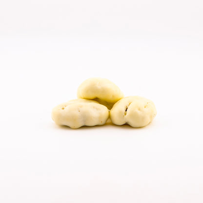 Three white chocolate pecans, arranged in a small pyramid on a seamless white background.