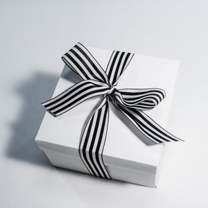 white gift box with black and white cabana ribbon tied in a bow