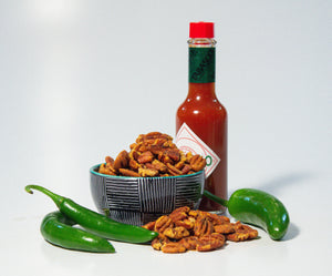 spicy pecans in bowl with jalapeno peppers and tabasco sauce